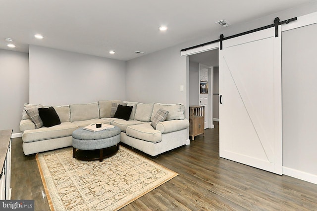 living room featuring a barn door and dark hardwood / wood-style flooring