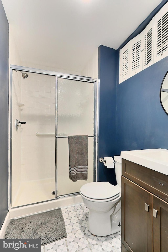 bathroom featuring vanity, toilet, tile patterned floors, and a shower with door