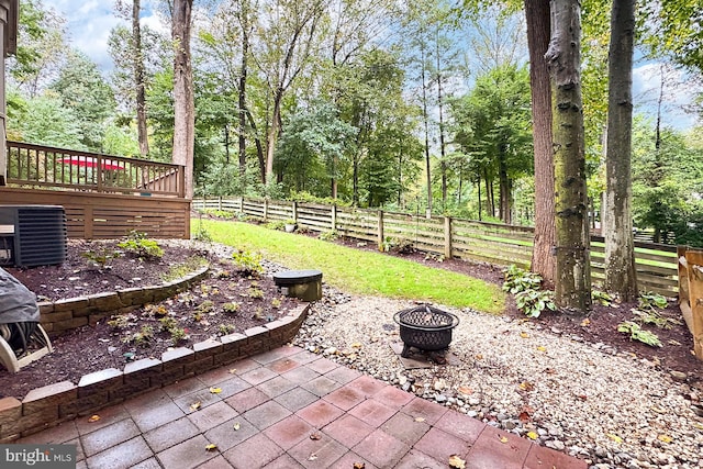 view of patio with central AC, a wooden deck, and an outdoor fire pit