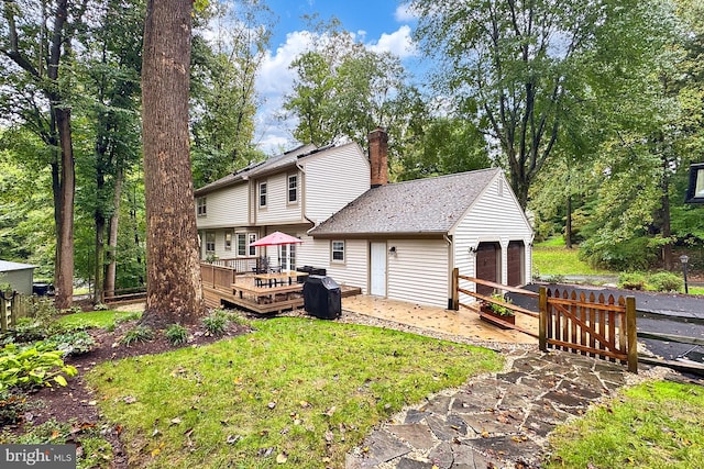 back of property featuring a lawn, a garage, and a wooden deck