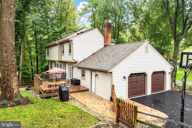 rear view of house with a deck and a garage