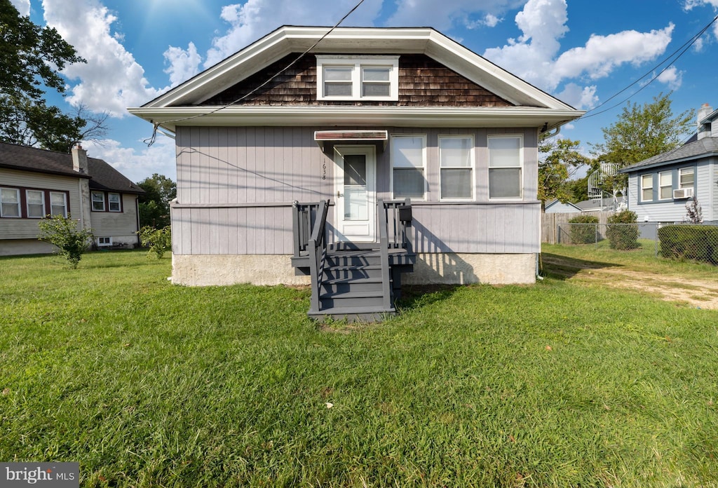 rear view of house with fence and a lawn