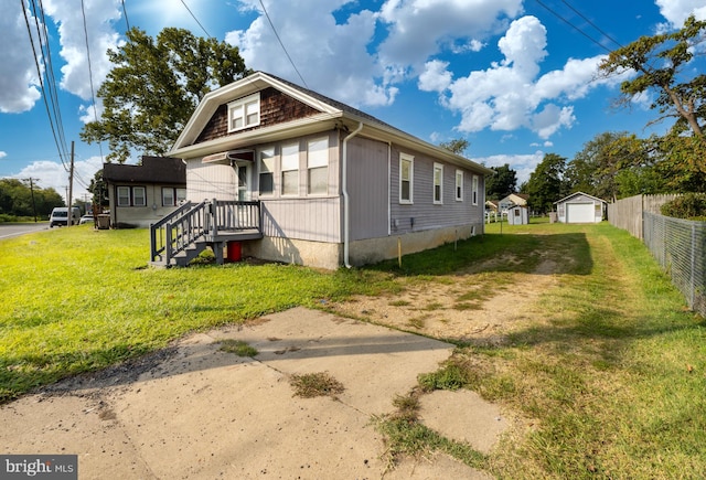 view of side of property featuring a lawn, a garage, and an outbuilding