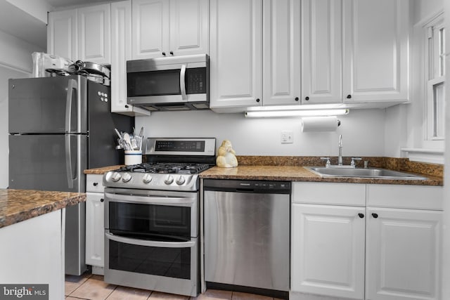 kitchen featuring stainless steel appliances, sink, white cabinets, and dark stone counters