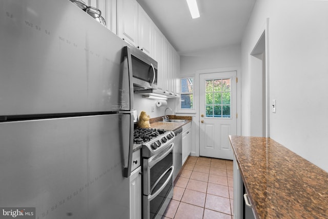 kitchen featuring appliances with stainless steel finishes, sink, white cabinetry, and light tile patterned flooring