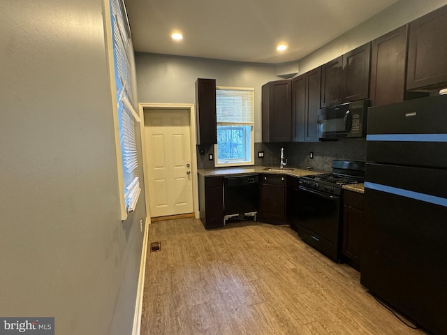 kitchen featuring light wood-type flooring, black appliances, sink, decorative backsplash, and dark brown cabinetry