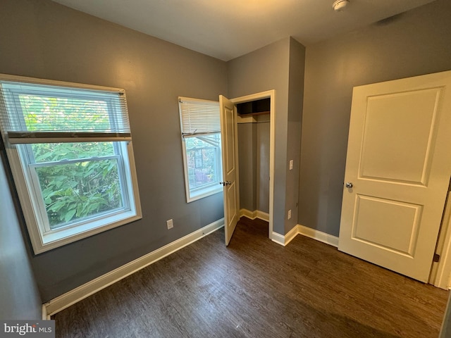 unfurnished bedroom featuring dark hardwood / wood-style floors, a closet, and multiple windows