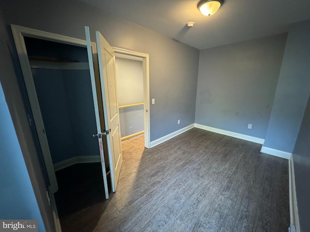 unfurnished bedroom with dark wood-type flooring and a closet