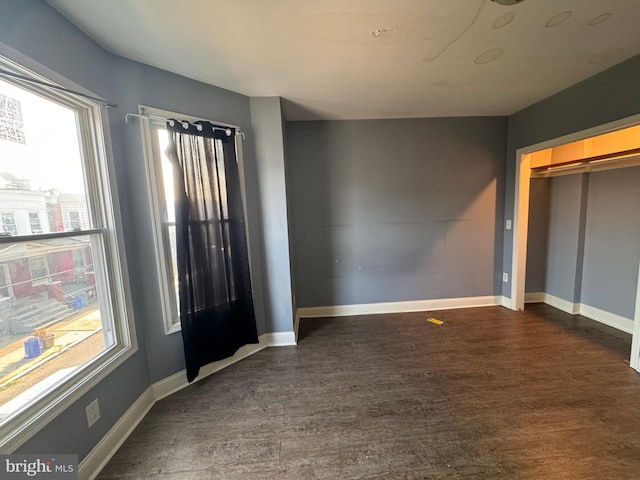 empty room featuring dark wood-type flooring and a healthy amount of sunlight