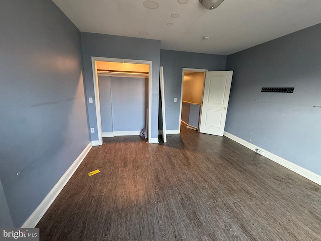 unfurnished bedroom with dark wood-type flooring and a closet