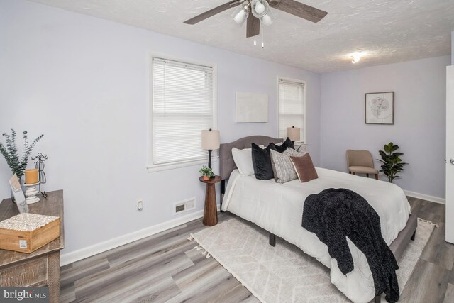 bedroom with ceiling fan, hardwood / wood-style floors, and multiple windows