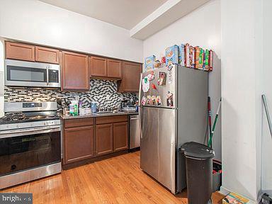 kitchen featuring stainless steel appliances, light hardwood / wood-style floors, and tasteful backsplash