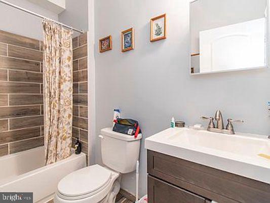 full bathroom featuring shower / tub combo with curtain, toilet, and vanity