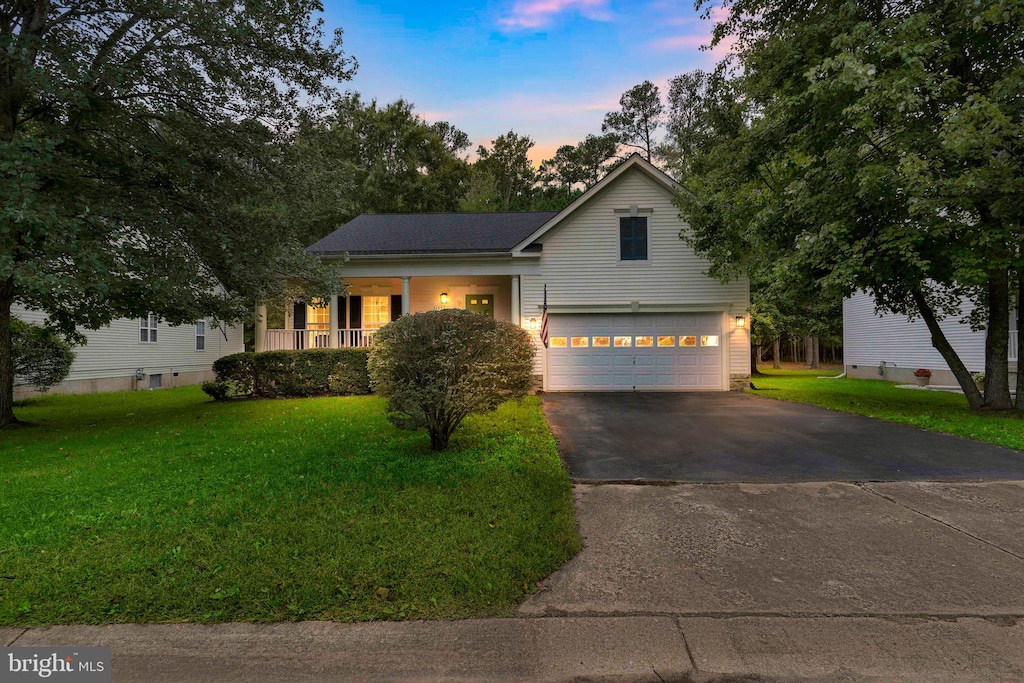 view of front of house with a garage, a yard, and a porch