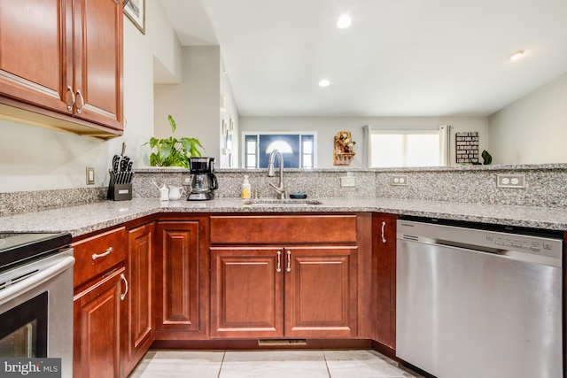 kitchen featuring light tile patterned floors, dishwasher, sink, and light stone countertops