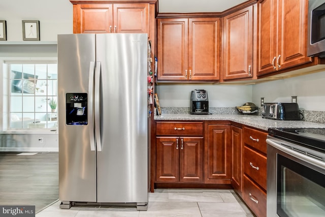 kitchen with appliances with stainless steel finishes, light hardwood / wood-style flooring, and light stone counters