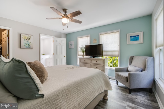 bedroom featuring ensuite bath, dark hardwood / wood-style floors, and ceiling fan