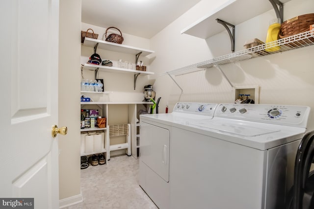 clothes washing area featuring light tile patterned floors and washer and clothes dryer