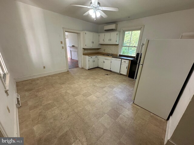 kitchen with a wall unit AC, white appliances, white cabinetry, a ceiling fan, and light floors