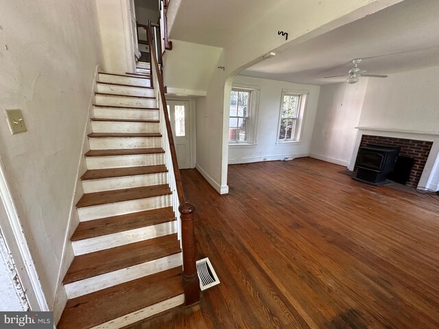 stairway with arched walkways, visible vents, a ceiling fan, wood finished floors, and baseboards