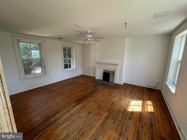 unfurnished living room featuring ceiling fan, dark wood-style flooring, a fireplace, visible vents, and baseboards