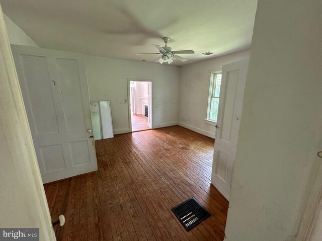 interior space featuring a ceiling fan, wood finished floors, visible vents, and baseboards