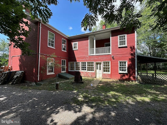 rear view of house featuring a balcony, a chimney, and an attached carport