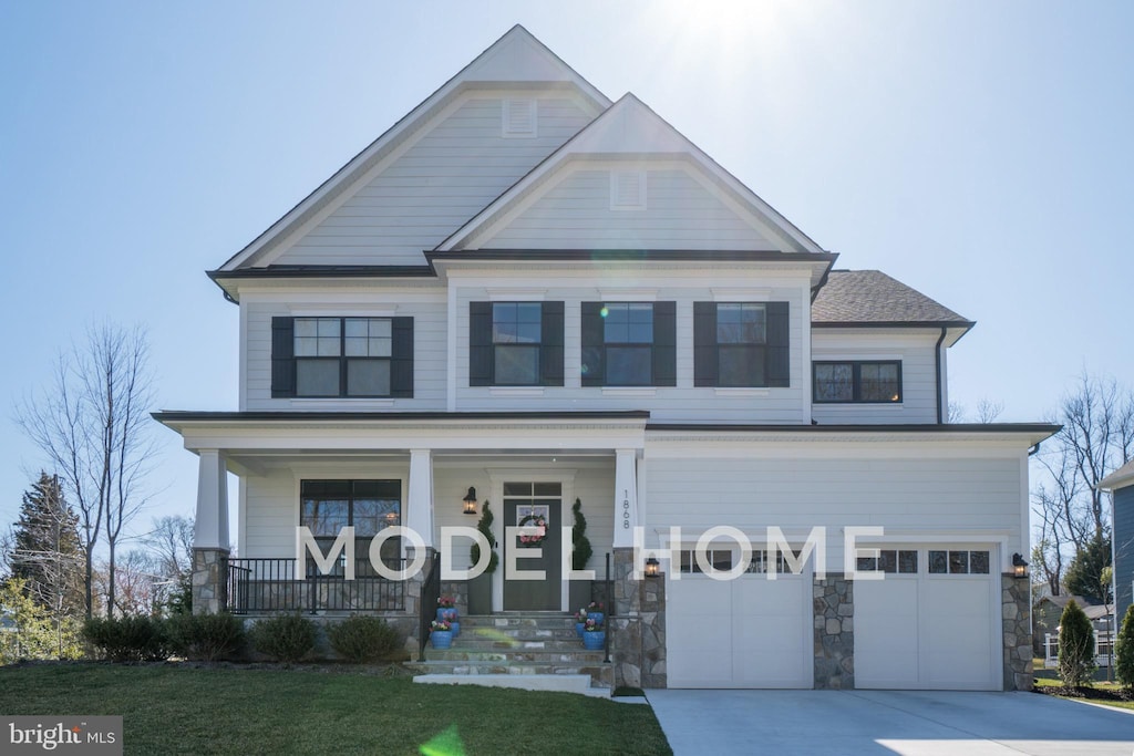 view of front of home with covered porch, a garage, stone siding, driveway, and a front lawn