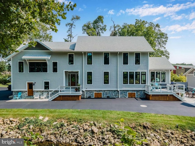 rear view of property featuring roof with shingles and a patio area