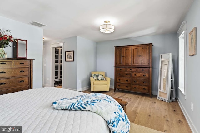 bedroom featuring a walk in closet, a closet, and light hardwood / wood-style floors