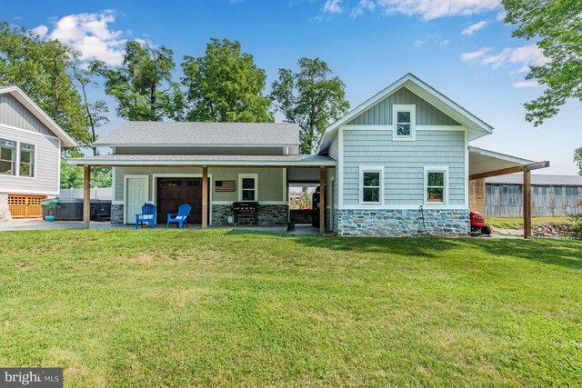 rear view of house featuring a jacuzzi and a yard