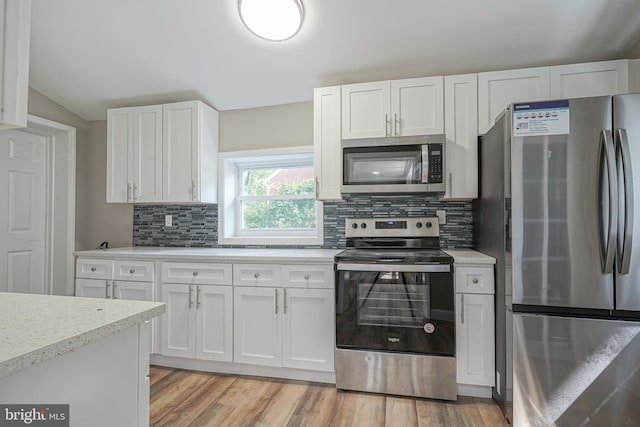 kitchen with backsplash, light wood-type flooring, appliances with stainless steel finishes, light stone counters, and white cabinets