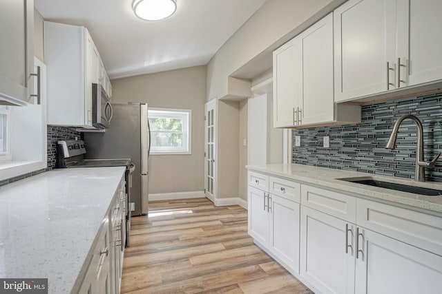 kitchen with backsplash, stainless steel appliances, lofted ceiling, and light wood-type flooring