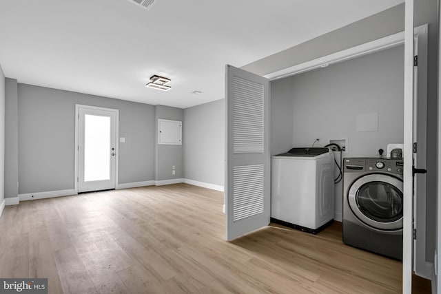 laundry room featuring washing machine and dryer and light hardwood / wood-style flooring