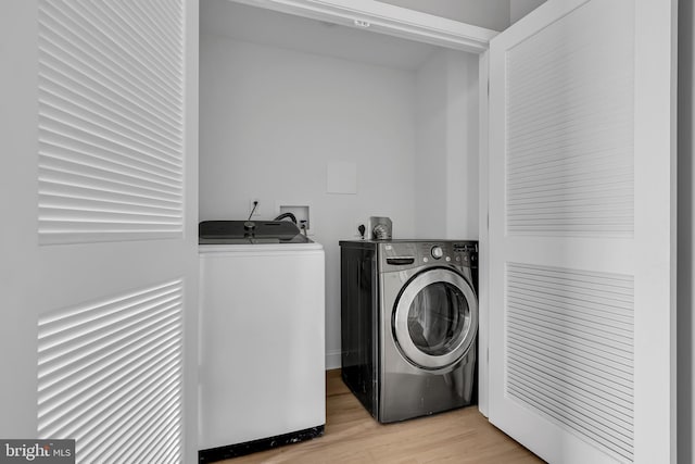 washroom featuring washing machine and clothes dryer and light hardwood / wood-style flooring