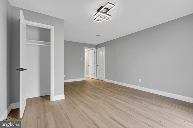 unfurnished bedroom with light hardwood / wood-style flooring and a closet