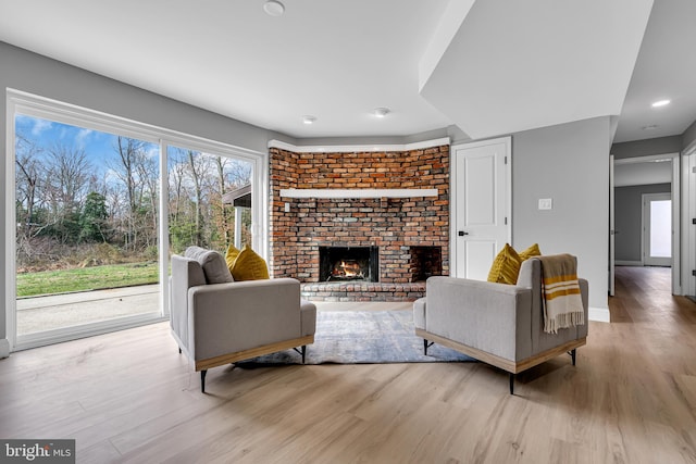 living room featuring light wood-type flooring and a brick fireplace