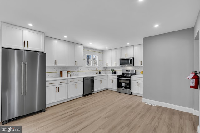 kitchen featuring appliances with stainless steel finishes, sink, light hardwood / wood-style flooring, and white cabinets