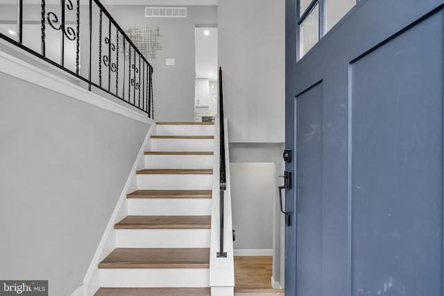 stairway featuring hardwood / wood-style flooring and a high ceiling