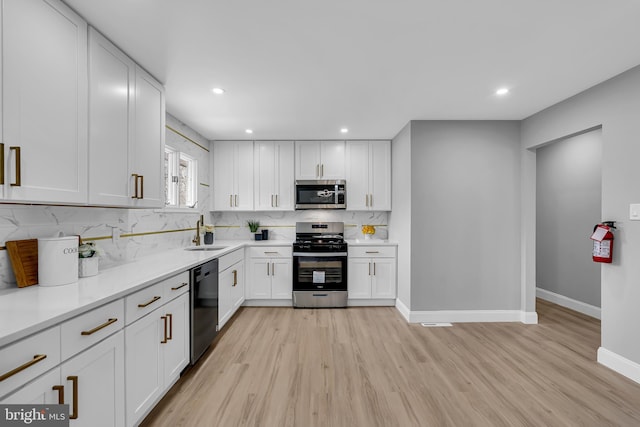 kitchen with white cabinetry, appliances with stainless steel finishes, sink, and light hardwood / wood-style flooring