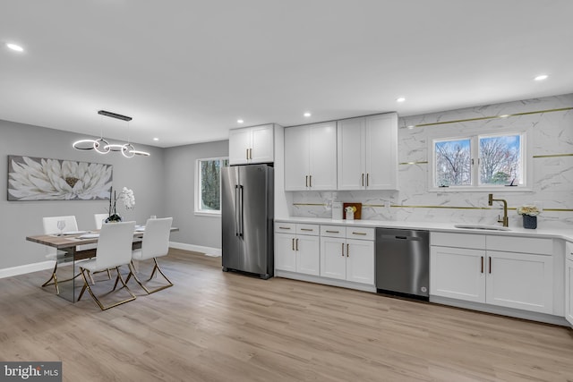 kitchen with white cabinets, stainless steel appliances, light hardwood / wood-style flooring, and a healthy amount of sunlight