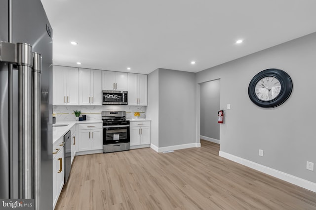 kitchen with white cabinetry, stainless steel appliances, light hardwood / wood-style flooring, and decorative backsplash