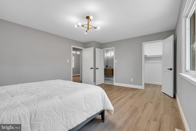 bedroom featuring a walk in closet, a closet, a notable chandelier, and light hardwood / wood-style floors