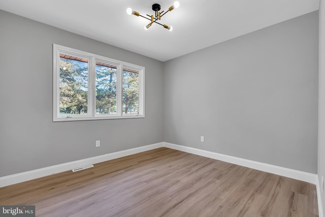 empty room with a notable chandelier and hardwood / wood-style flooring