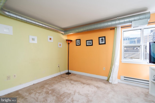 empty room with a baseboard heating unit, light carpet, and baseboards