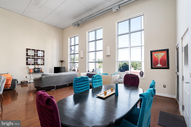 dining area with a high ceiling, plenty of natural light, and wood finished floors