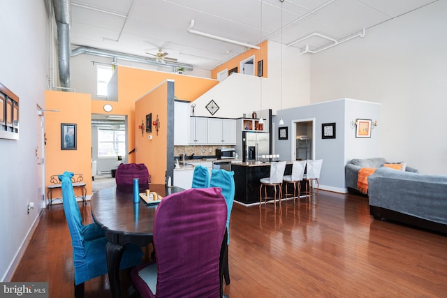 dining area with baseboards, a high ceiling, and wood finished floors