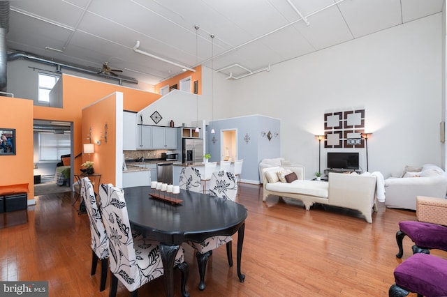 dining space featuring a ceiling fan, a high ceiling, and hardwood / wood-style flooring