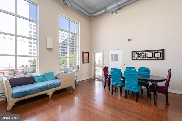 interior space featuring a towering ceiling, baseboards, a city view, and wood finished floors