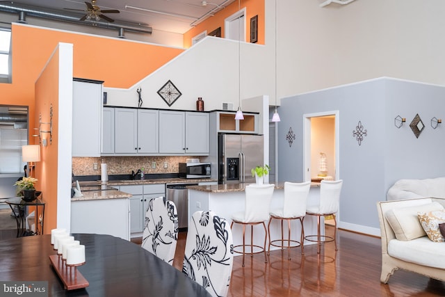 kitchen with a center island, a breakfast bar, a towering ceiling, stainless steel appliances, and decorative backsplash